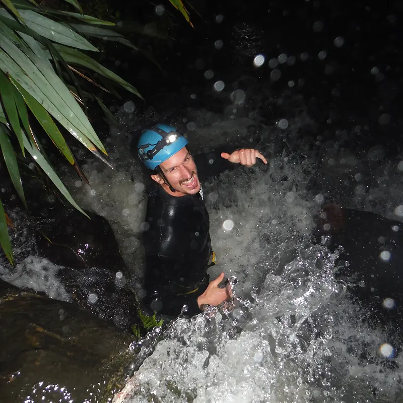 Canyoner splashing through a waterfall at night