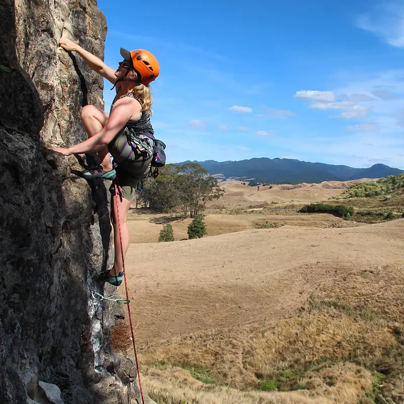 Climber on a sport route with rolling farmland and hills behind