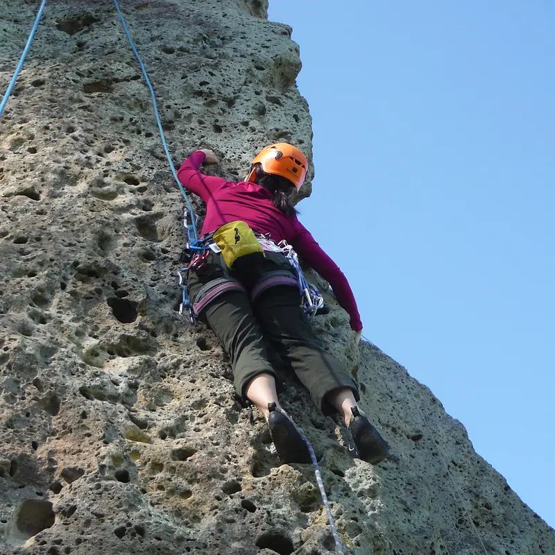 Lead climber clipping quickdraws on pocketed rock