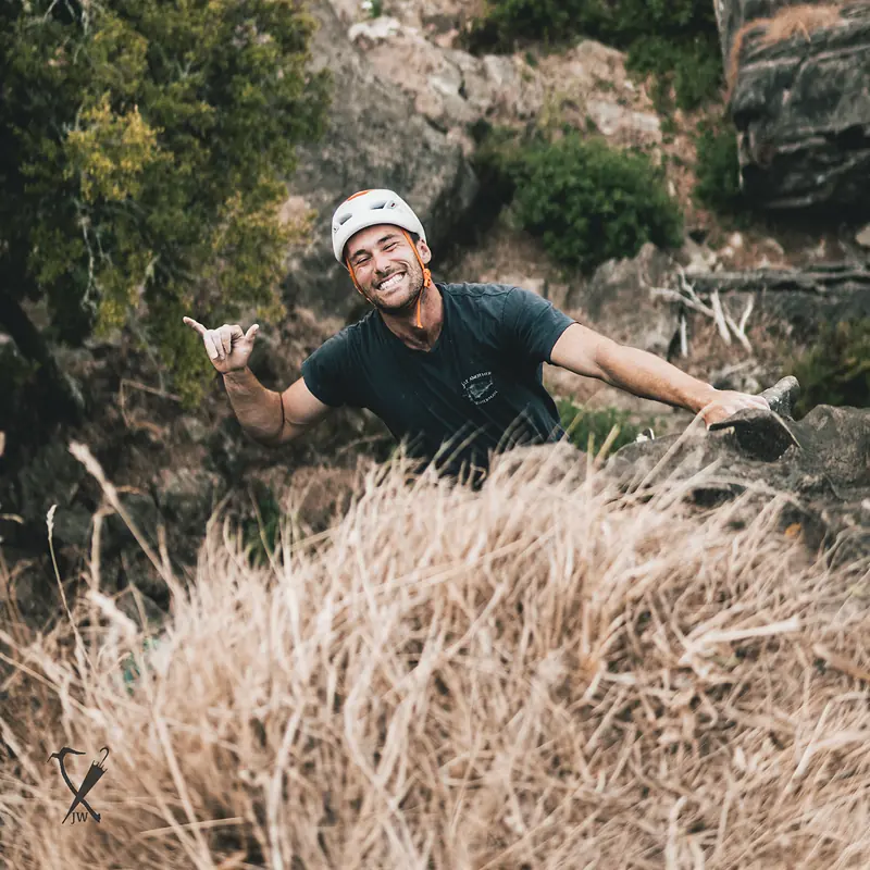 Smiling climber topping out on a sport route