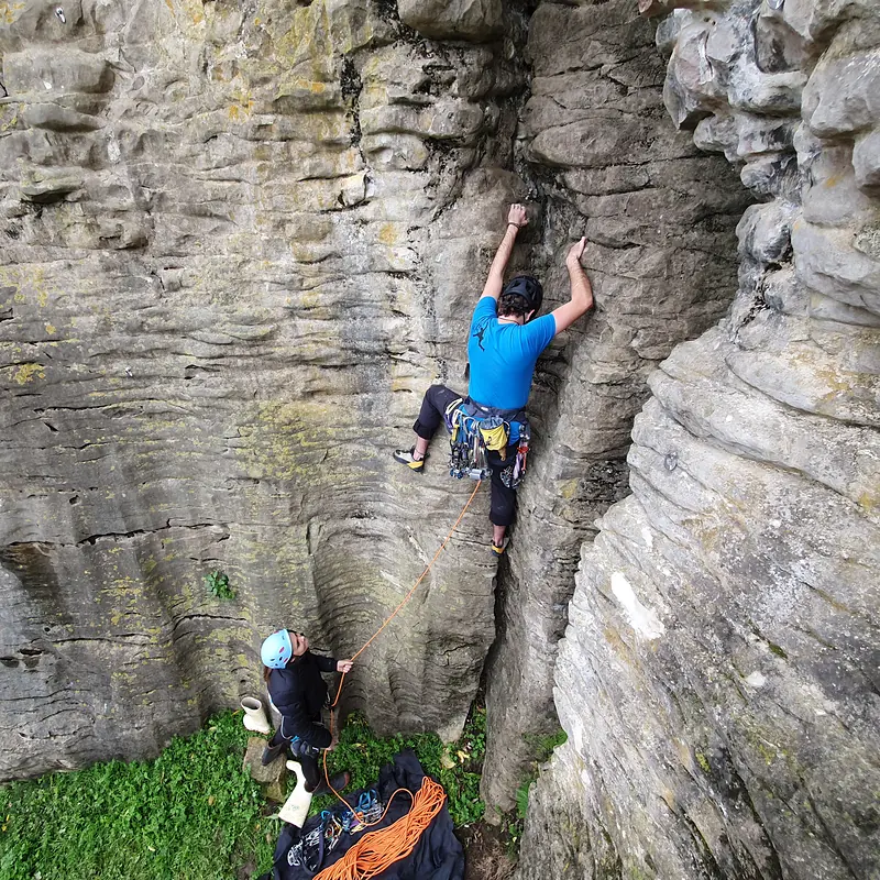Trad climber in a crack with belayer below