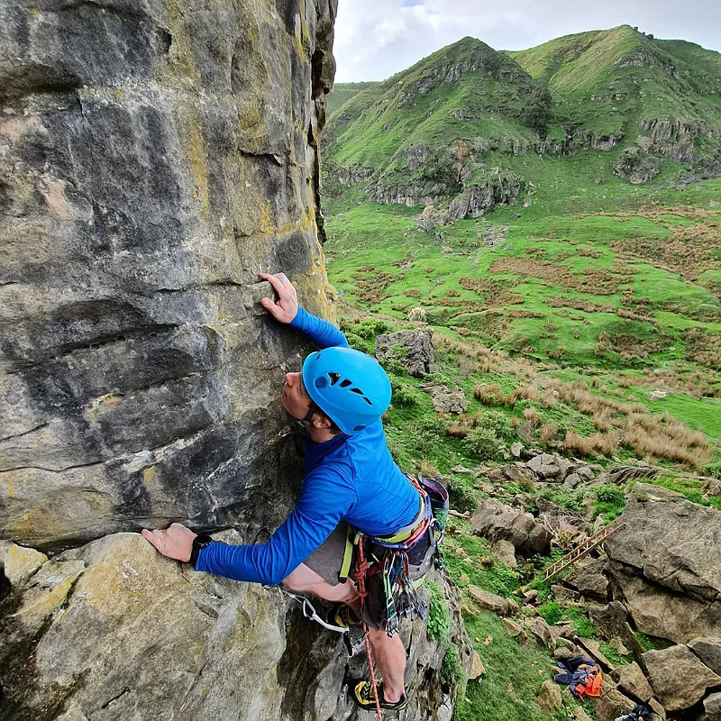 Climber placing gear on a trad climbing route